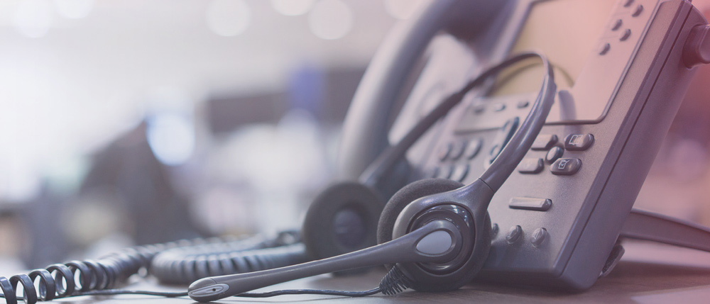 headset leaning against a desk phone