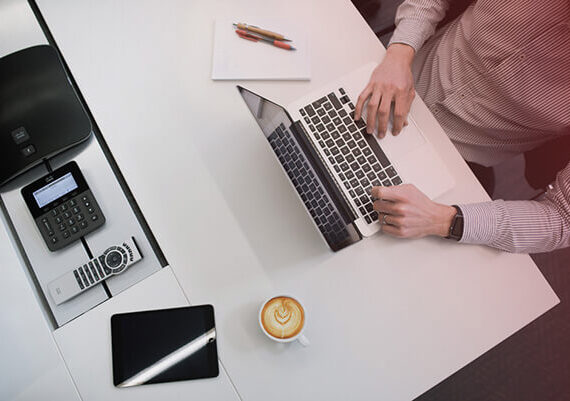 overhead view of a work desk with someone typing on a laptop