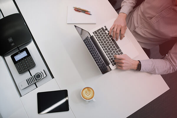 overhead view of a work desk with someone typing on a laptop